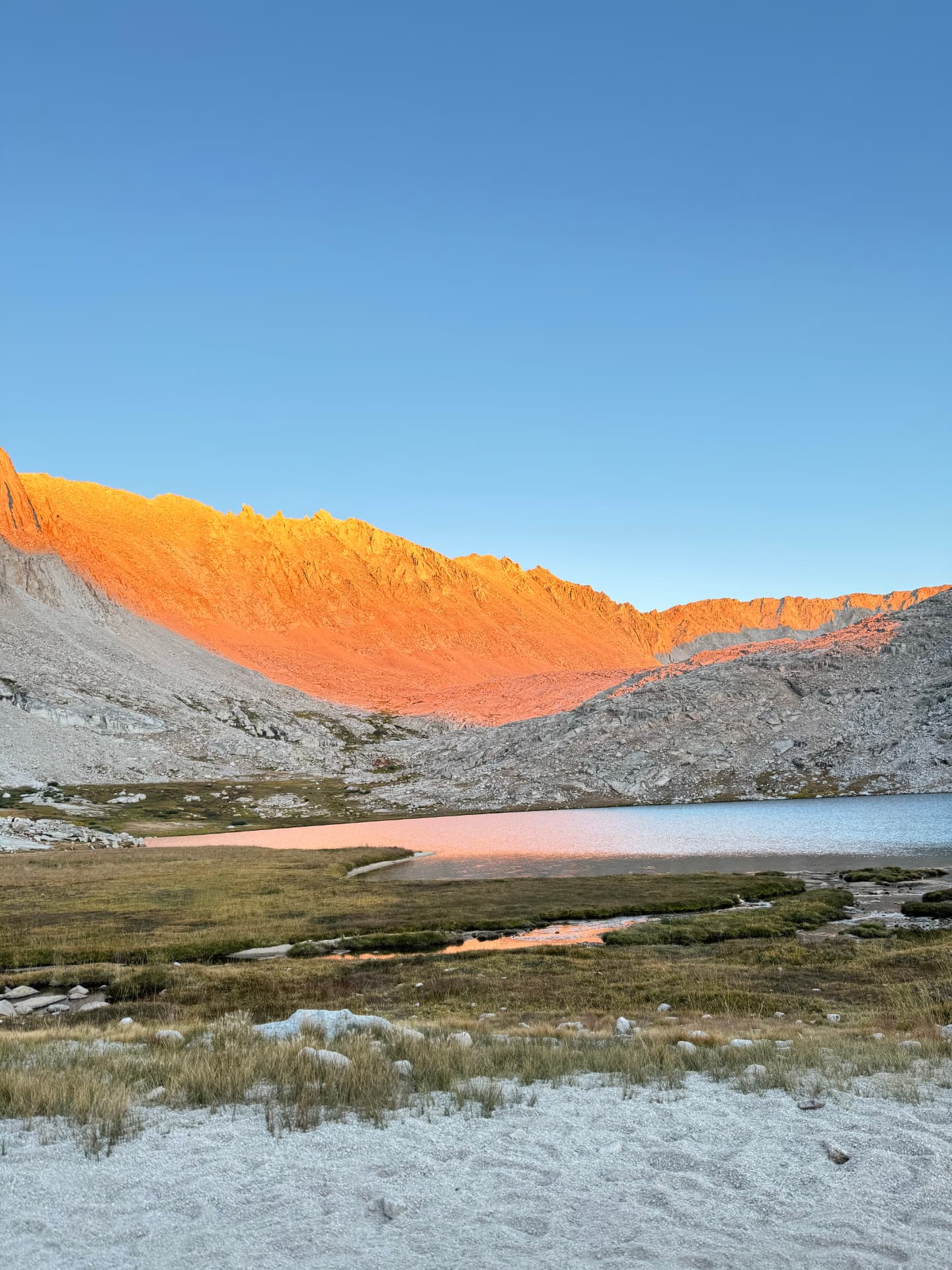 Alpine lake at sunrise with a glowing mountain ridge reflected in still water